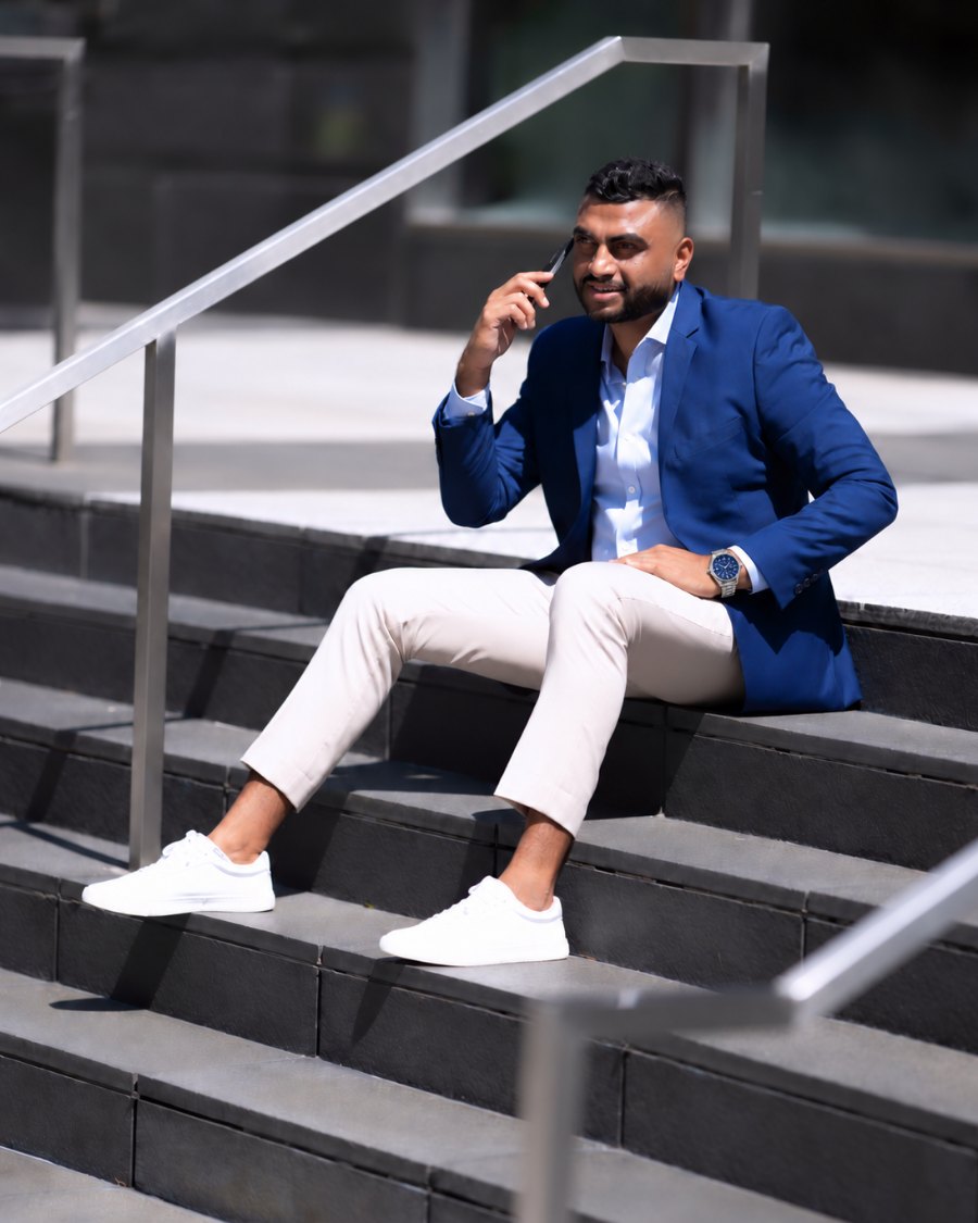 Divyesh Dabhi on a phone call, sitting on the steps outside an office building